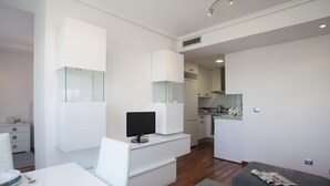 Een moderne, compacte leefruimte met een kitchenette, een eethoek en een zithoek.
