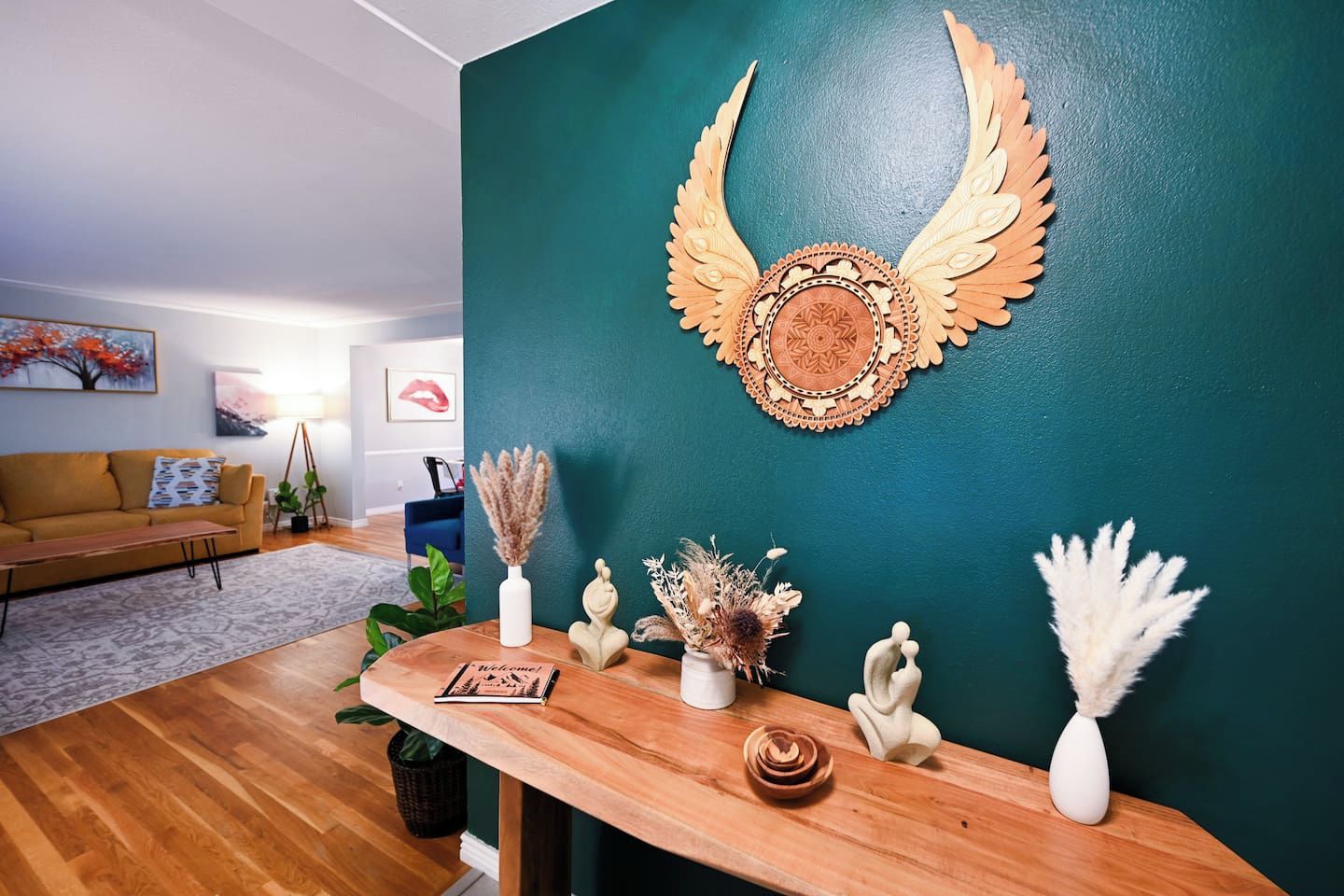 A living room with a teal wall, a wooden coffee table, and a decorative wall piece.