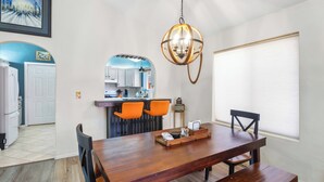 Un comedor con una mesa de madera, sillas anaranjadas y una lámpara colgante.