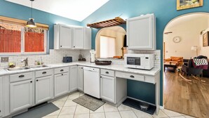 Una cocina moderna con armarios blancos, un microondas y un lavamanos.