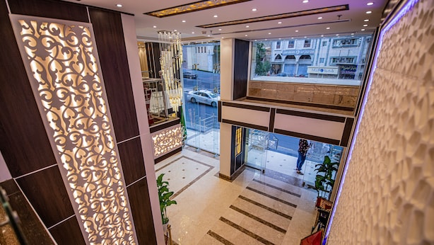 A modern hotel lobby with a decorative partition, a chandelier, and a view of the street outside. - Saraya Al Misk Hotel (Makkah)