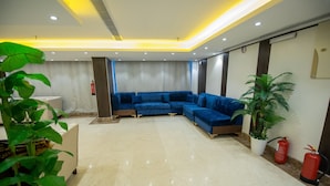 A modern lobby with a blue sectional sofa, a marble floor, and potted plants. - Saraya Al Misk Hotel (Makkah)