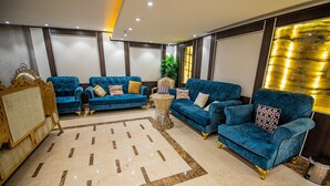 A spacious living area with two blue sofas, a marble floor, and a small side table. - Saraya Al Misk Hotel (Makkah)