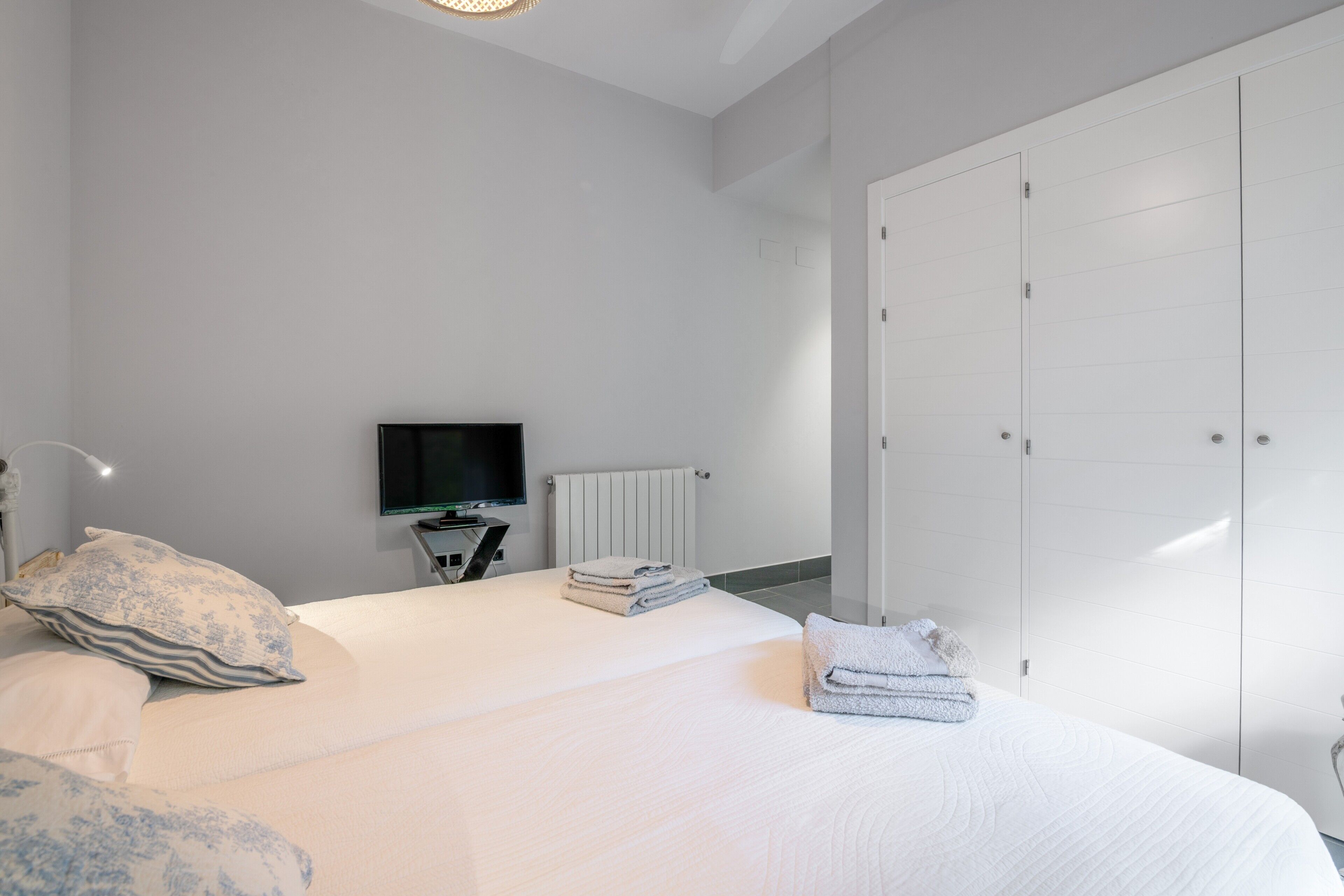 A bedroom with a bed, a TV, a radiator, and a wardrobe.