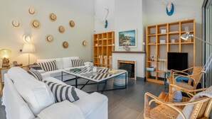 Ein modernes Wohnzimmer mit einer Couch, einem Couchtisch, Korbstühlen, einem Kamin und einem Bücherregal.
