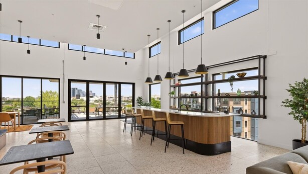 Un interior espaiós i modern amb alts sostres, grans finestres, una zona de bar central i diferents disposicions de seients.