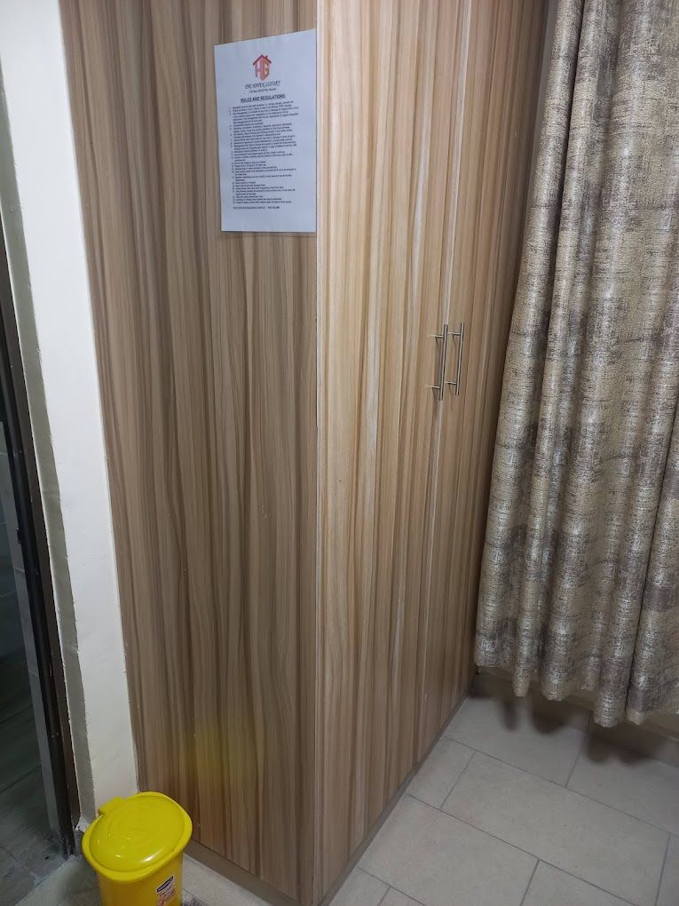 Une armoire en bois avec une pancarte, un seau jaune et un rideau.