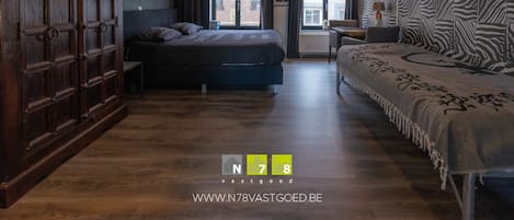 Et moderne hotelværelse med et stort skab, seng, sofa og udsigt over byen.