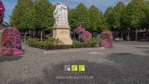 A statue in a public square surrounded by trees and flower arrangements. - Studio: Stefan Evers Mid long term rentable (Maaseik)