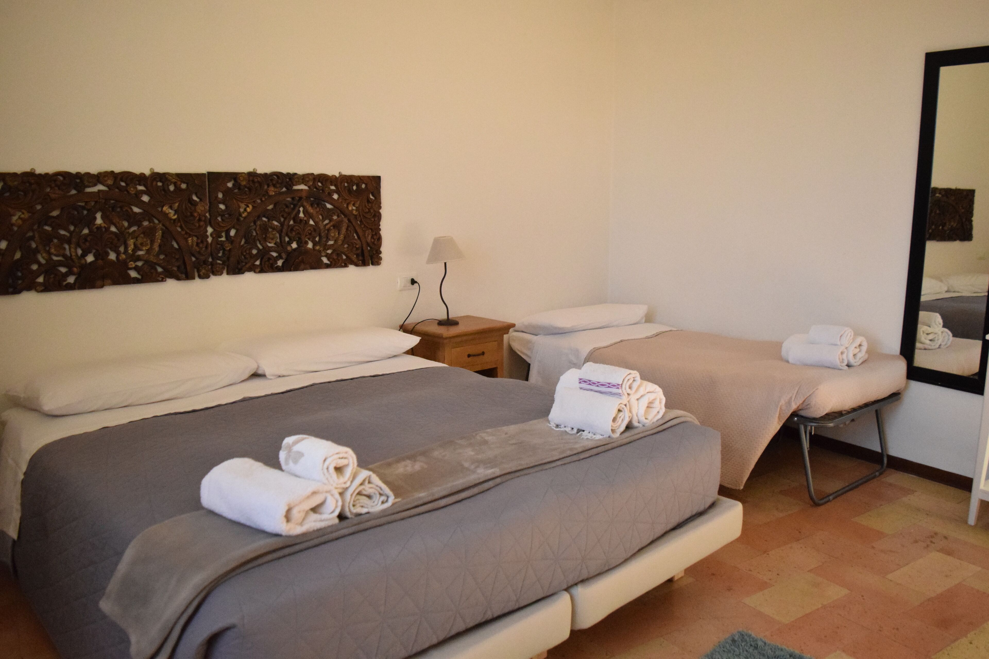 Une chambre d’hôtel avec deux lits, une table de chevet, une lampe et un miroir.