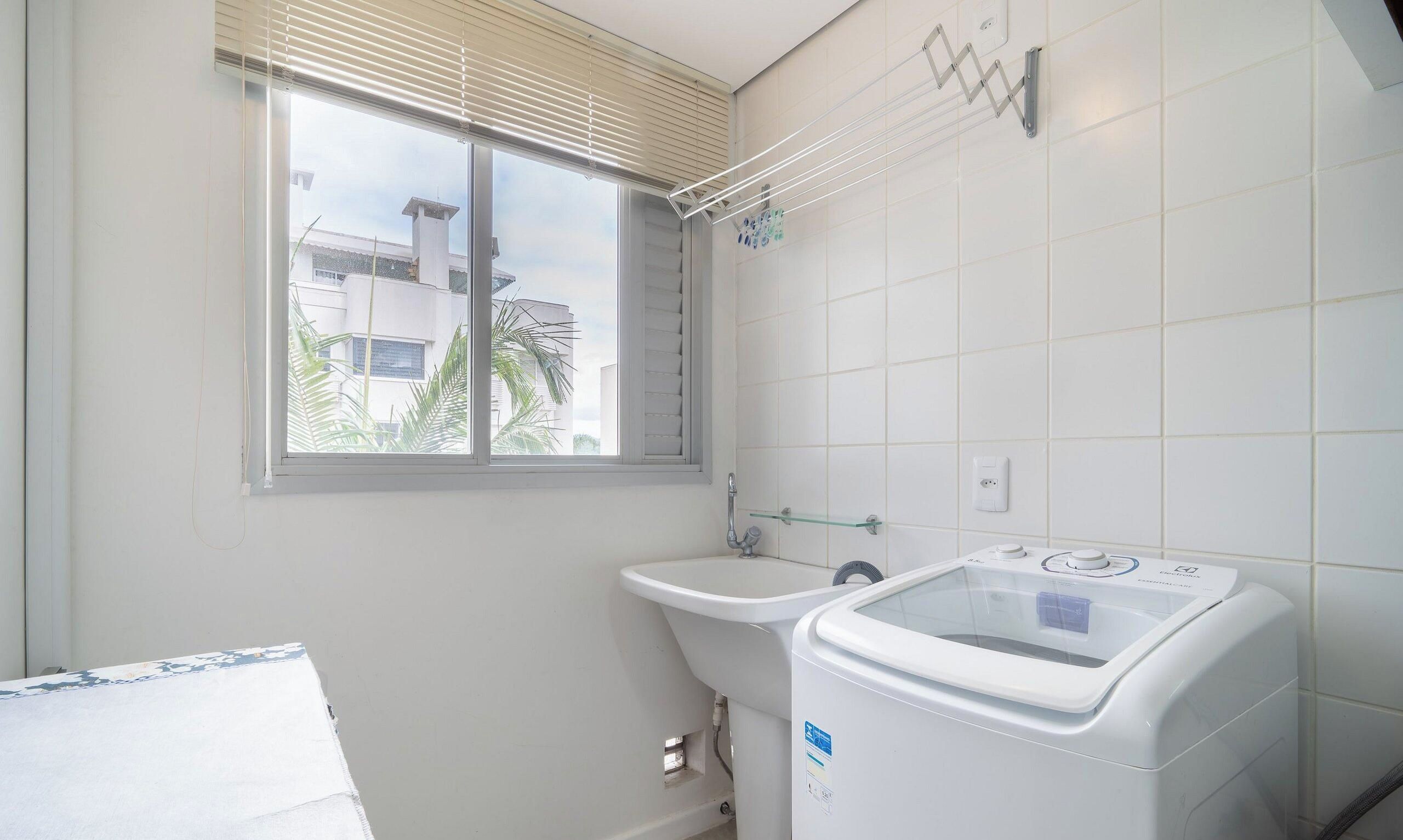 A small, clean bathroom with a window, a sink, and a washing machine.