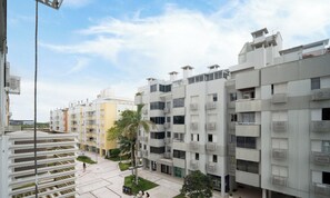 Un immeuble d’appartements moderne doté de balcons, d’une cour intérieure et offrant une vue sur un ciel dégagé.