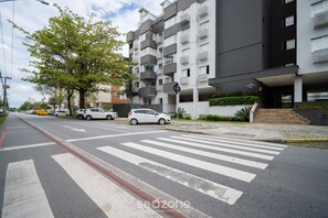 A modern apartment building with balconies, a pedestrian crossing, and a clear sky. - Apt 700 m From Praia de Jurere Aav0306 (Florianópolis)