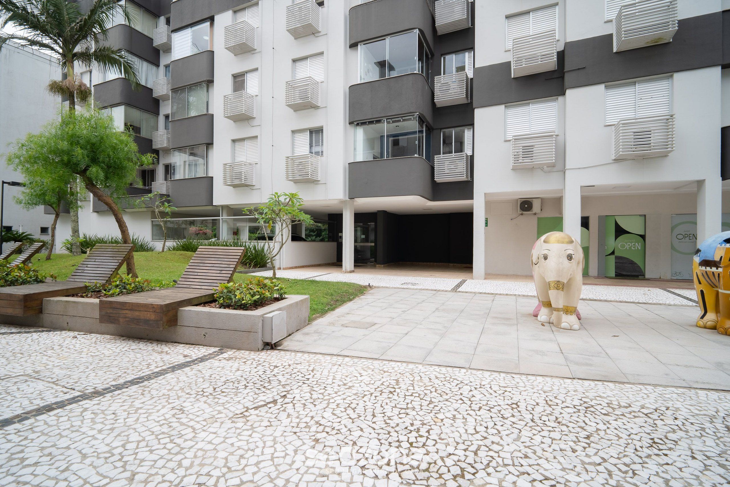 A modern building with multiple balconies, a central entrance, and a decorative elephant statue.