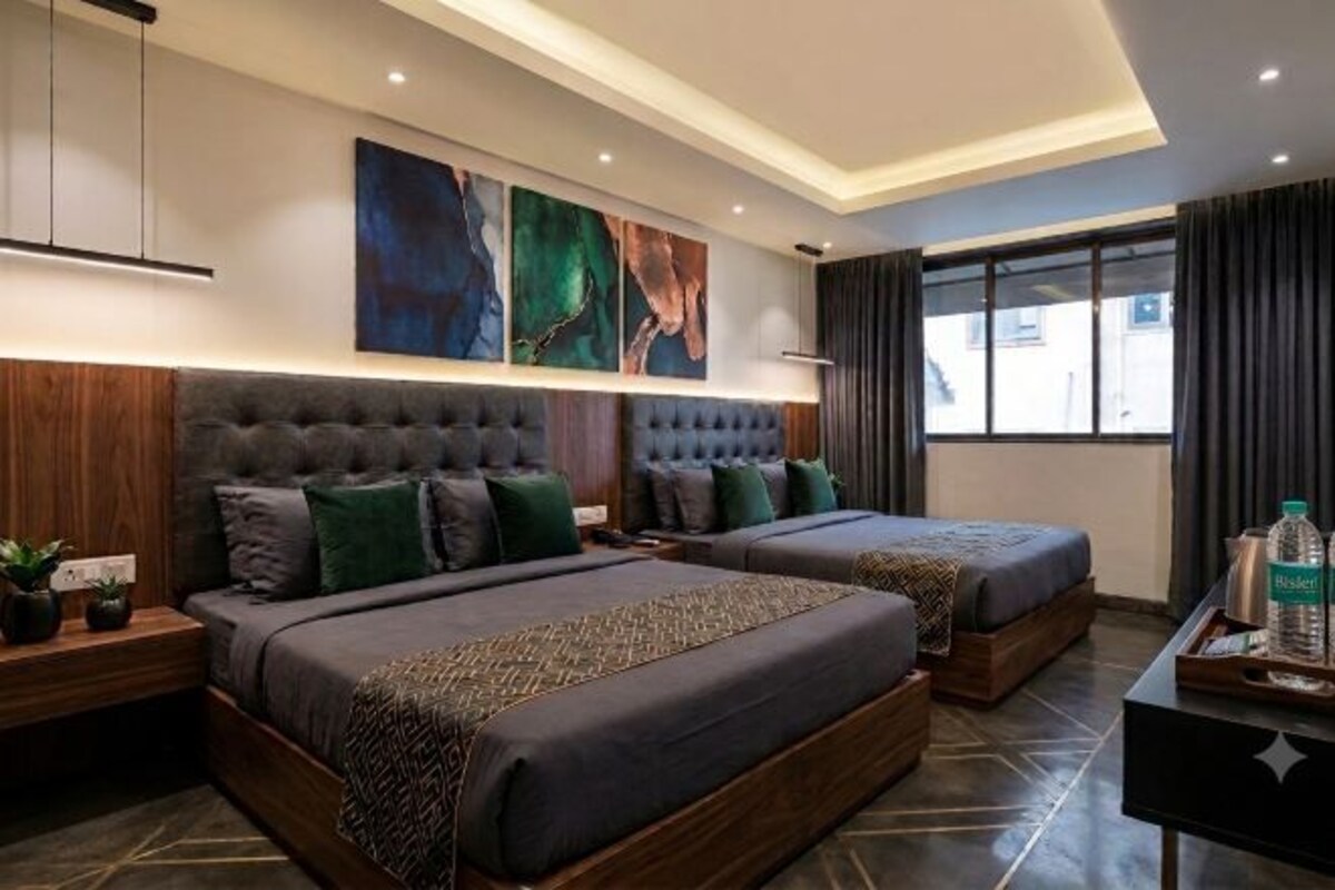 A modern hotel room with two beds, a desk, and artwork on the wall.