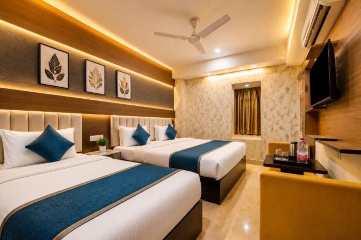 A hotel room with two beds, a TV, a ceiling fan, and a small table.