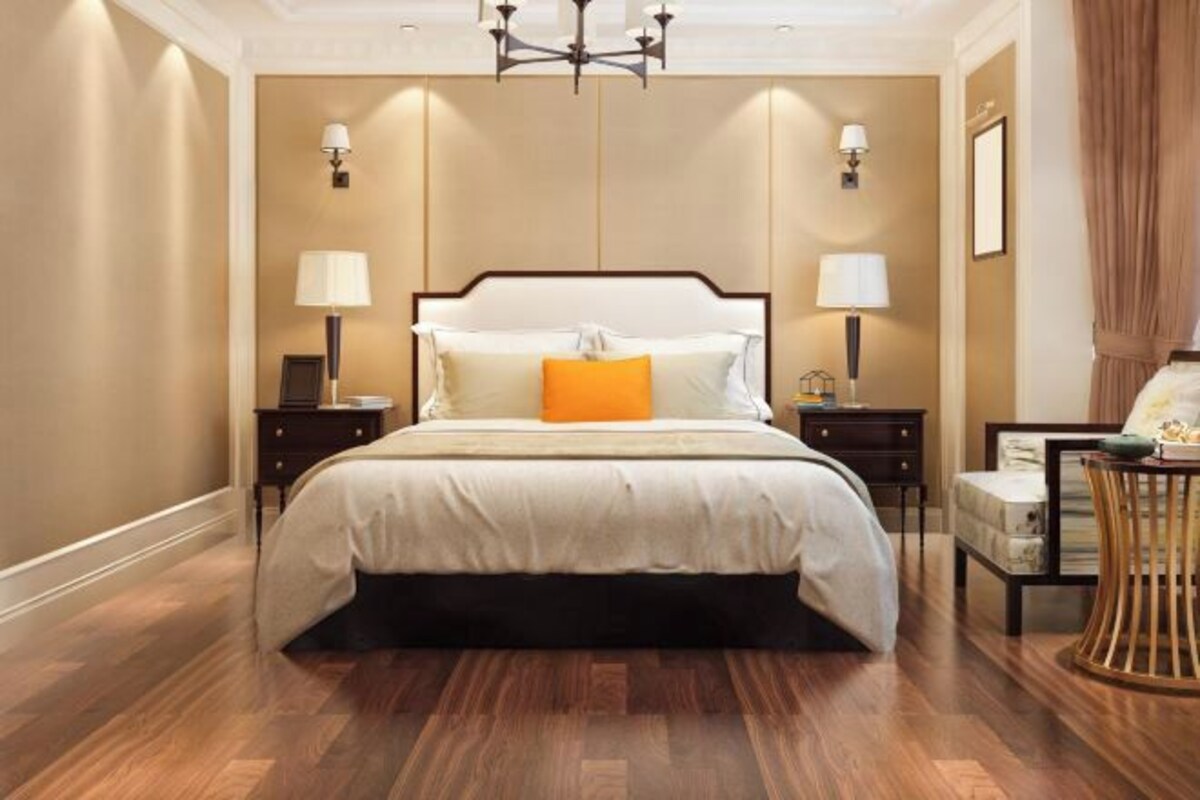 A bedroom with a large bed, two bedside tables, a chandelier, and a chair.