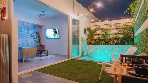 Un espacio exterior moderno con patio, una mesa de comedor y una pantalla de televisión.