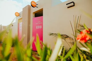 A modern building with a pink door labeled "E08" and a sign above it. - 1 BDRM Suite for Any Budget, Private In-Suite Plunge Pool, Near Eagle Beach (Oranjestad)