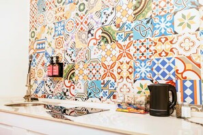 A kitchen with a colorful tile backsplash, a coffee maker, and a spice rack. - 1 BDRM Suite for Any Budget, Private In-Suite Plunge Pool, Near Eagle Beach (Oranjestad)
