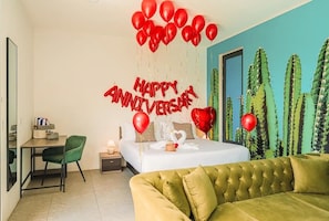 A modern bedroom with a bed, a green sofa, a desk, and a cactus wall. - 1 BDRM Suite for Any Budget, Private In-Suite Plunge Pool, Near Eagle Beach (Oranjestad)