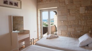 A bedroom with two beds, a dresser, a mirror, and a balcony with a view of the sea. - Pantanassa Villas - Erato with Sea View (Agia Marina)