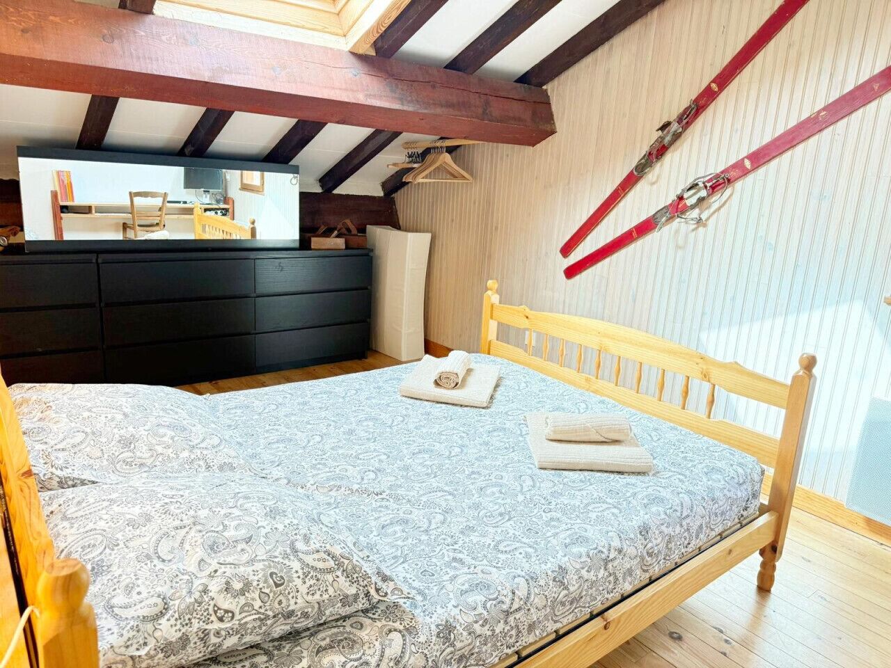A bedroom with a wooden bed, a dresser, and a window with a view.