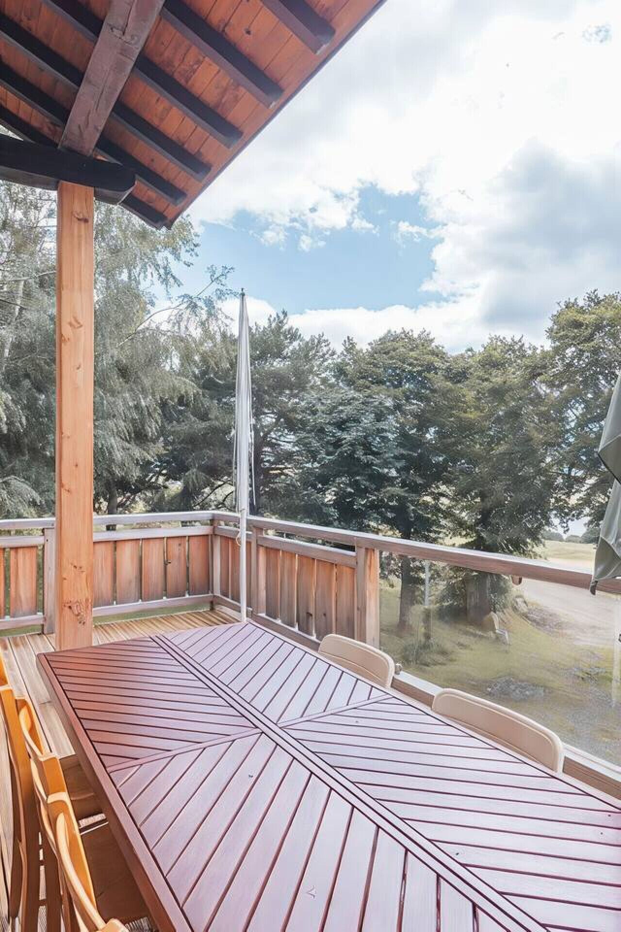 A wooden deck with a table and chairs, overlooking a forested area.