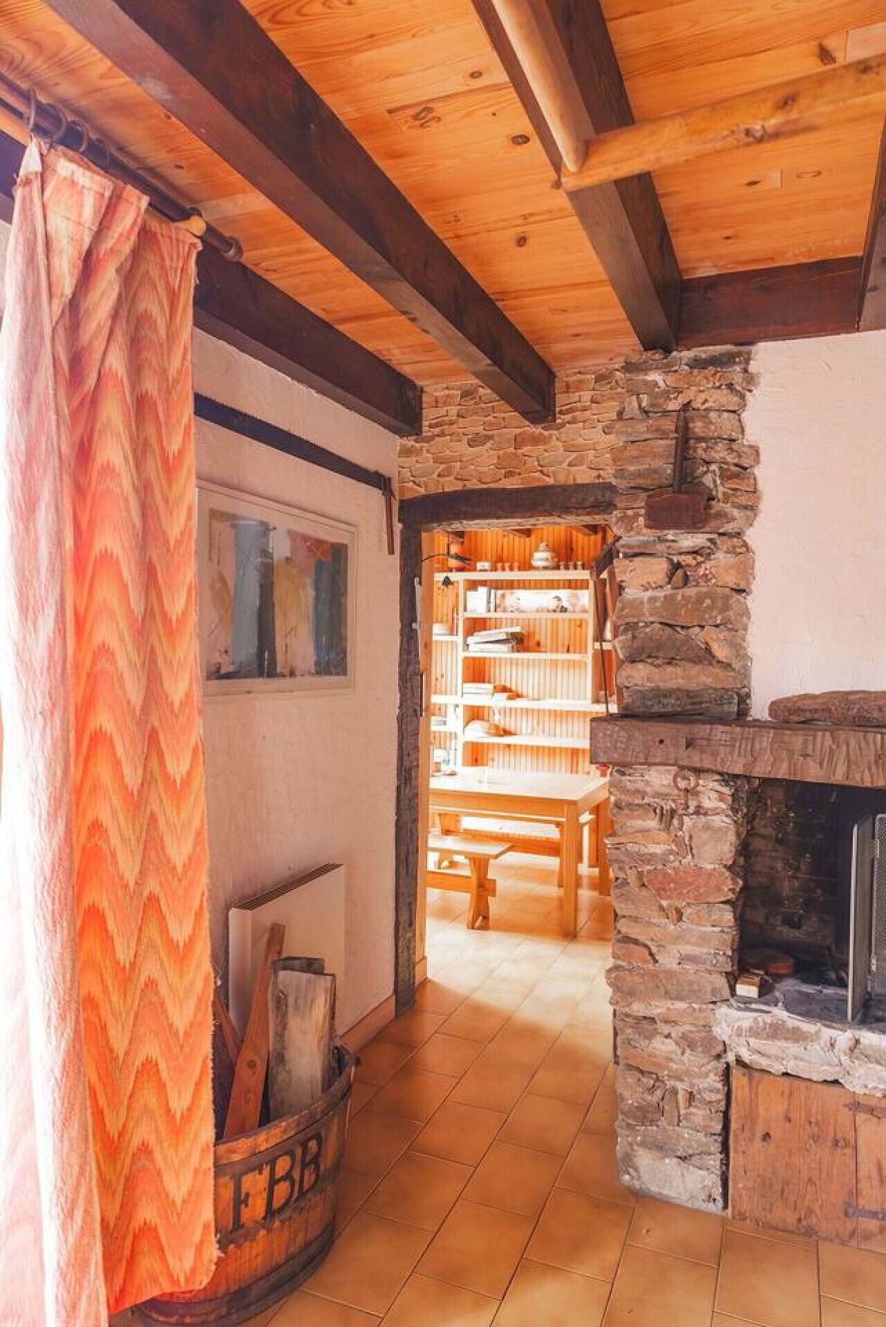 Une pièce chaleureuse avec une cheminée en pierre, des poutres apparentes et une esthétique rustique.