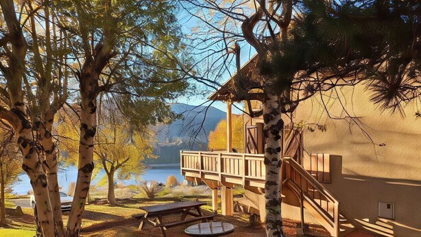Une terrasse en bois avec un escalier menant à un chalet situé au bord d’un lac.