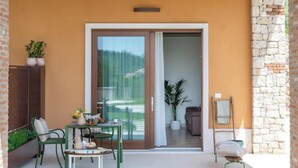 Un balcon avec une table et des chaises, une plante en pot et une porte-fenêtre coulissante donnant sur un espace intérieur.