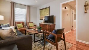 A living room with a sofa, armchairs, a coffee table, and a television.