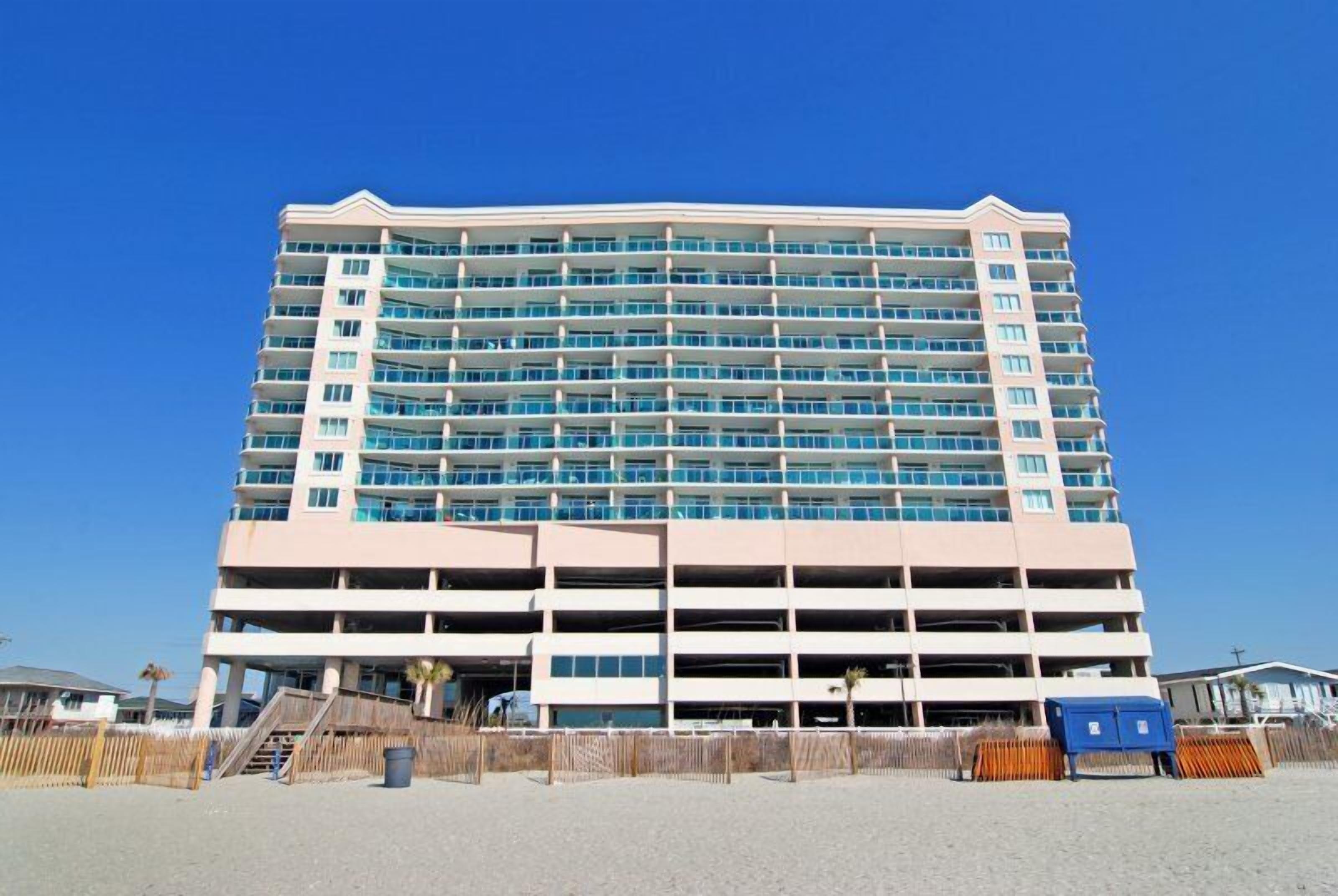 Un hôtel à plusieurs étages doté d’un parking central et situé en bord de mer.