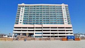 Un hotel a più piani con un parcheggio centrale e posizione fronte spiaggia.