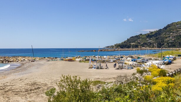 A beach with boats and a rocky shoreline. - Next to the Beach by Wonderful Italy (Ospedaletti)