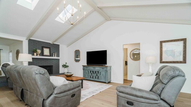 A spacious loft-style living room with high ceilings, a fireplace, a television, and two leather recliners. - West Texas Hideout • Homey Texas-Style Comfort (Amarillo)