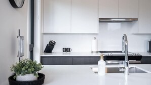 Una cocina moderna con armarios blancos, un lavamanos de acero inoxidable y un bloque para cuchillos negro.