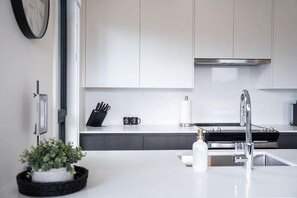 Una cocina moderna con armarios blancos, un lavamanos de acero inoxidable y un bloque para cuchillos negro.
