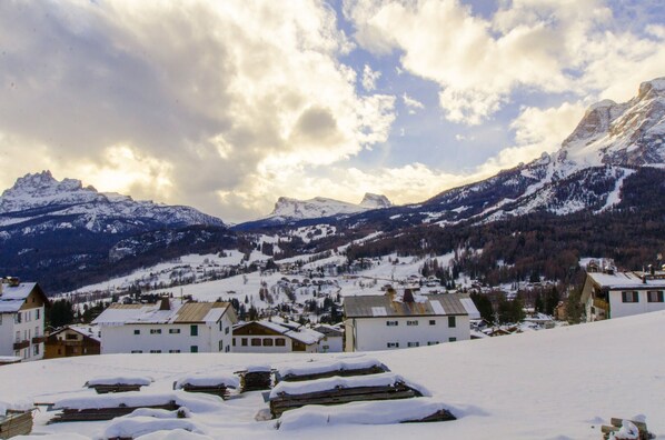 Uma aldeia coberta de neve com edifícios tradicionais, montanhas ao fundo e um céu limpo.