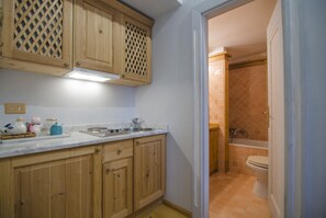 Uma cozinha com armários de madeira, uma pia e bancada com diversos objetos.