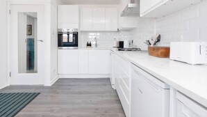 Eine moderne Küche mit weißen Schränken, einem eingebauten Backofen, einer Mikrowelle und einem Toaster.