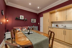 Un coin repas avec une table en bois, des chaises et une bouteille de vin. On y trouve également une cuisine avec des placards en bois et un évier.