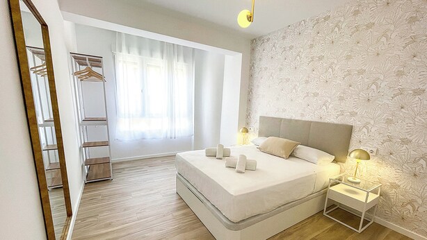 Une chambre moderne avec un grand lit, des tables de chevet, une armoire et un miroir.