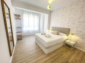 Een moderne slaapkamer met een groot bed, nachtkastjes, een kledingkast en een spiegel.