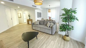 Un salon moderne avec un canapé gris, une table basse noire et une plante en pot.