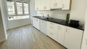 Une cuisine moderne avec des meubles blancs, un plan de travail noir et une fenêtre équipée de stores.