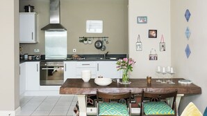 Eine moderne Küche mit weißen Schränken, einer Edelstahl-Dunstabzugshaube und einem Essbereich mit einem Holztisch und Stühlen.
