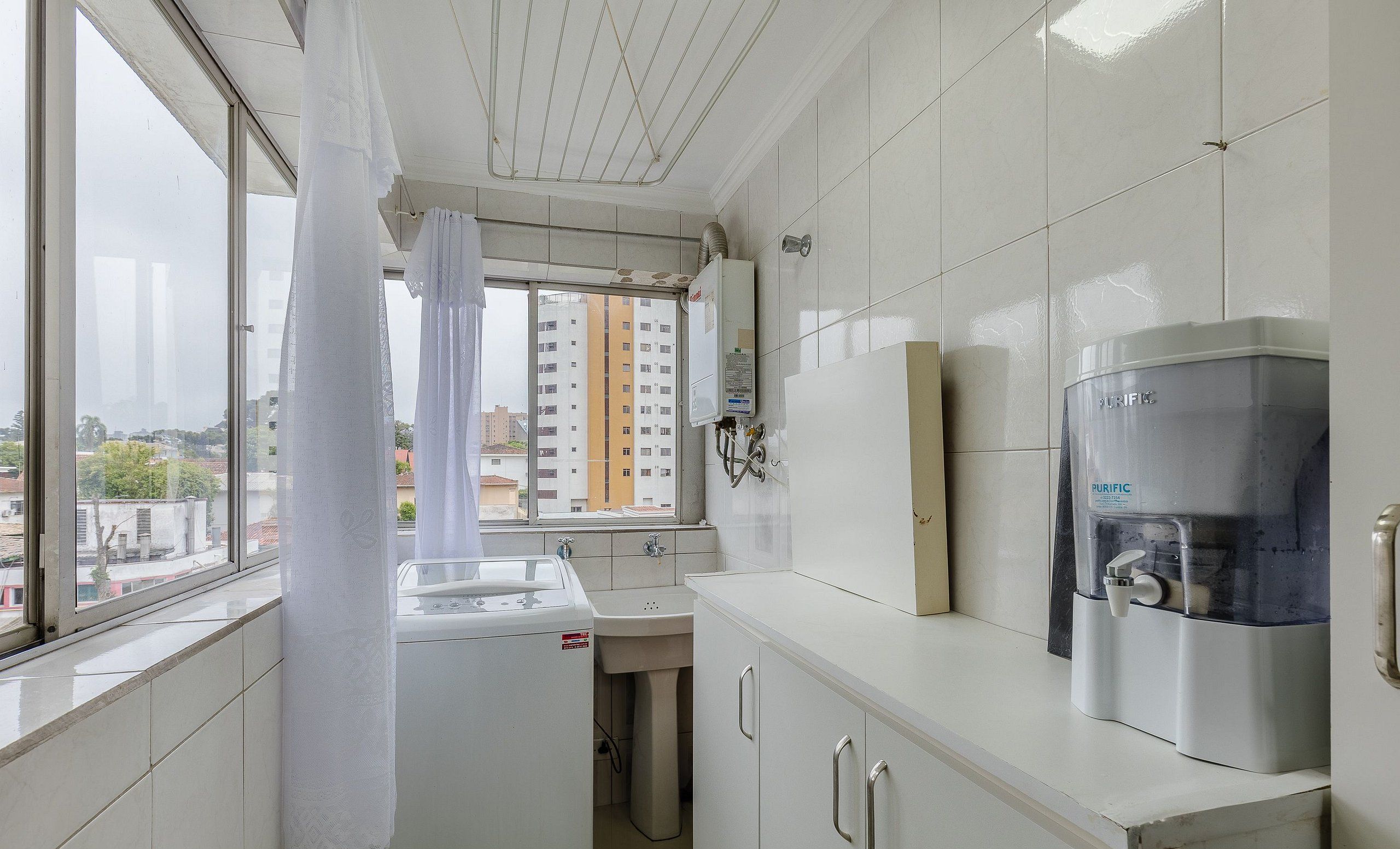 A compact kitchen with a window, a water purifier, and a sink.