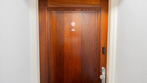 Uma porta de madeira com placa de proibido fumar e fechadura eletrônica.
