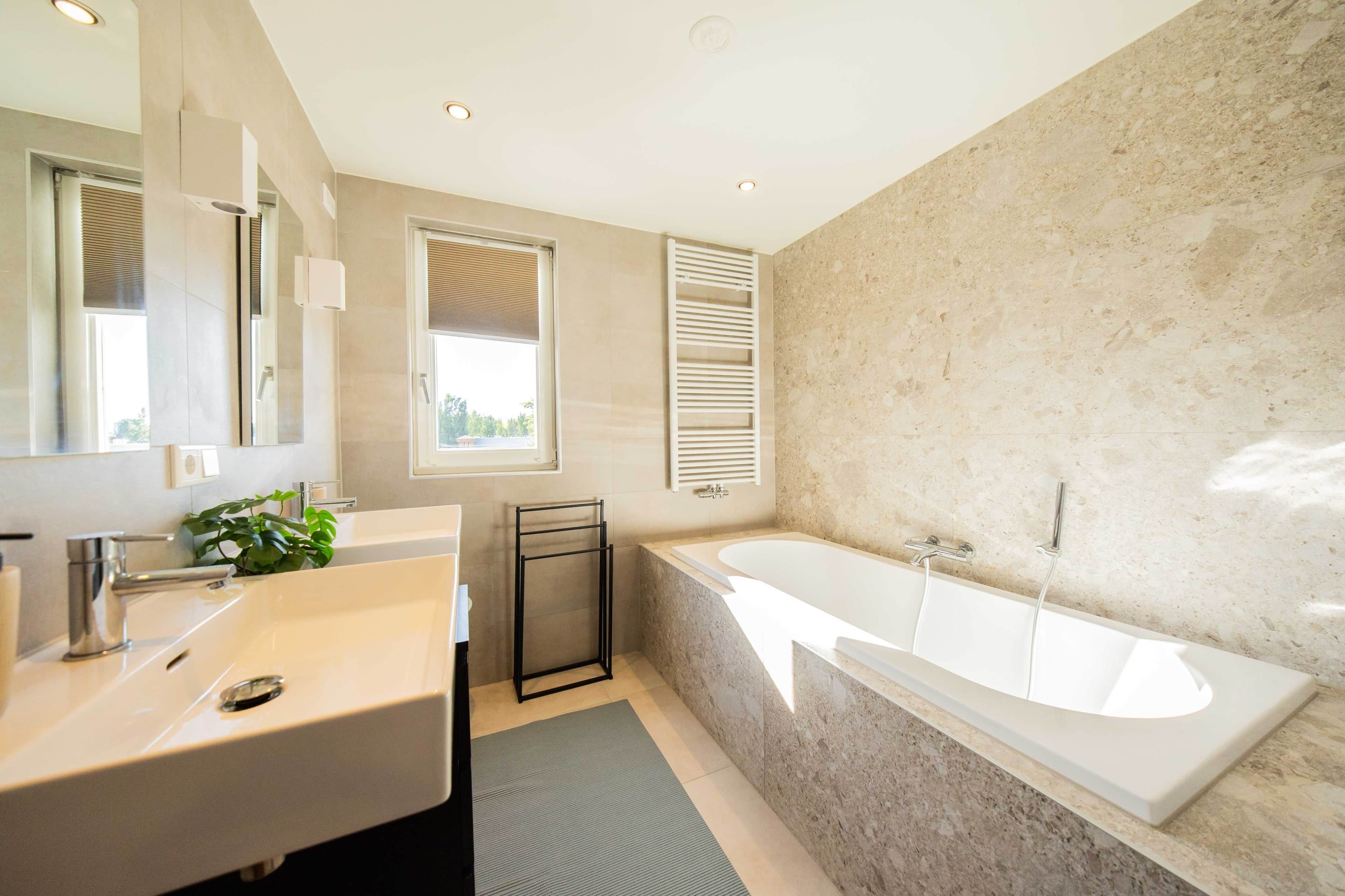 A modern bathroom with a large bathtub, a sink, and a mirror.